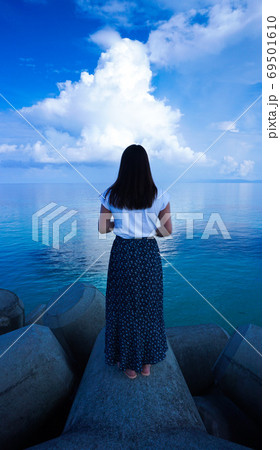海に浮かぶ白い雲とたたずむ女性 69501610