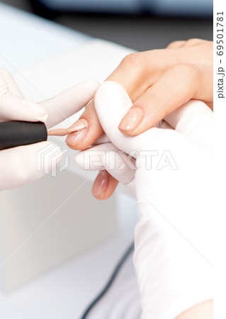 Manicure master applying beige nail polish Manicure master applying beige nail polish 69501781