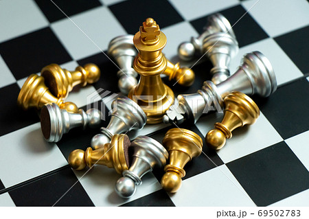 Gold king chess piece win over lying down pawn on black background