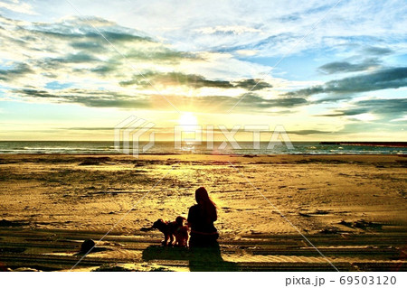 夕日を見ながら犬の散歩をする女性 69503120