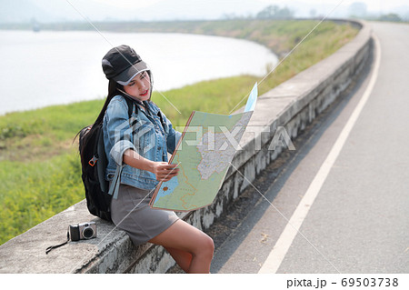 Young asian traveler with backpack searching direction on location map and using smart phone Young asian traveler with backpack searching direction on location map and using smart phone 69503738