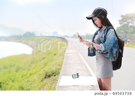 Young asian traveler with backpack searching direction on location map and using smart phone Young asian traveler with backpack searching direction on location map and using smart phone 69503739