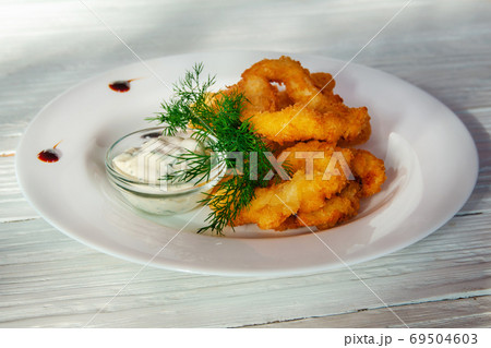 Deep-fried breaded onion rings on a plate with herbs 69504603