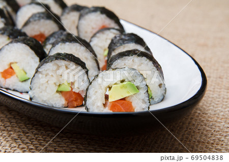 Sushi rolls in nori seaweed with avocado and red fish on ceramic plate Sushi rolls in nori seaweed with avocado and red fish on ceramic plate 69504838