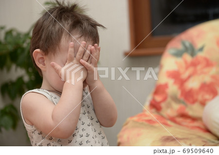 Boy playing hide-and-seek game at home. Portrait of boy male clothing eyes with hands Boy playing hide-and-seek game at home. Portrait of boy male clothing eyes with hands 69509640