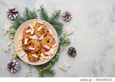 Christmas ginger cookies with chocolade on a beige plate decorated with a spruce branch 69509925