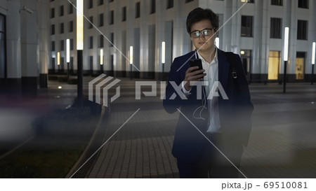 Man in black suit with phone and earphones, night shot lens flare 69510081