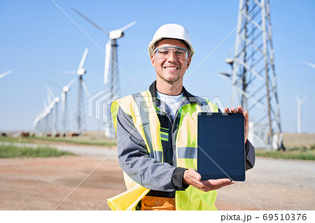 Manual worker holding tablet on windmills background Manual worker holding tablet on windmills background 69510376