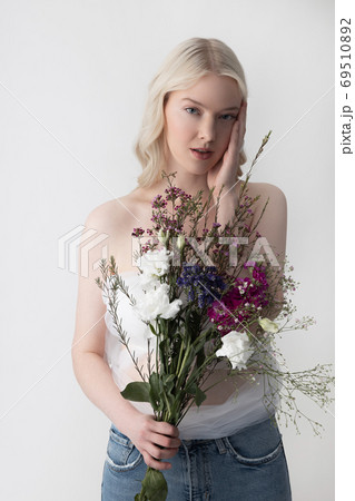 Charming young woman with flowers standing against white background Charming young woman with flowers standing against white background 69510892