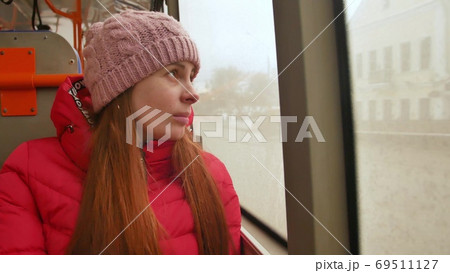 Close-up shot of a young sad woman traveling by bus on a dull rainy day. She looking out the wet Close-up shot of a young sad woman traveling by bus on a dull rainy day. She looking out the wet 69511127