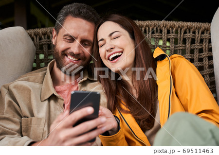 Happy young couple using modern smartphone outdoors 69511463