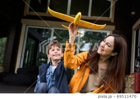 Happy mother and son playing with toy plane outdoors 69511470