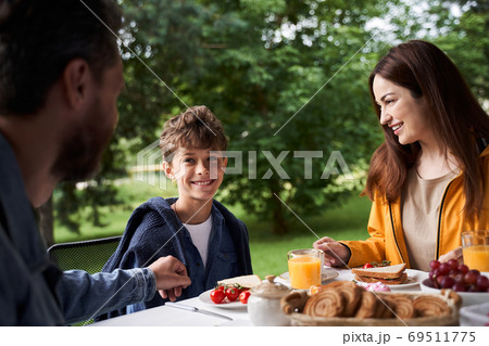 Loving parents having breakfast with cute son outdoors 69511775