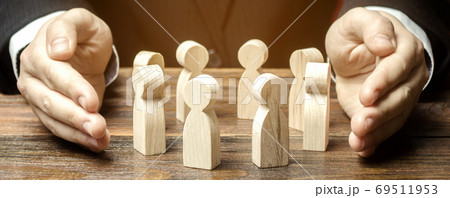 Businessman defending his team with a gesture of protection. Care for employees. Life insurance. Security and safety in a business team. Human resources. Social protection. Wooden figures Businessman defending his team with a gesture of protection. Care for employees. Life insurance. Security and safety in a business team. Human resources. Social protection. Wooden figures 69511953