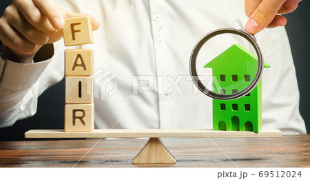 Wooden blocks with the word Fair and a wooden house. Fair value of real estate and housing. Property valuation. Home appraisal. Housing evaluator. Legal transparent deal. Apartment purchase / sale. 69512024