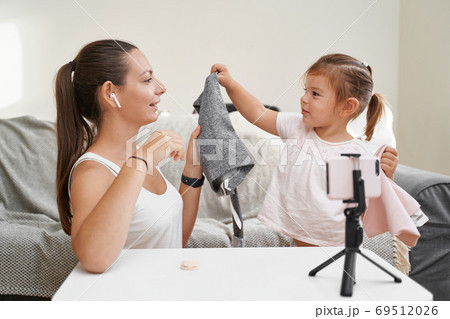 Mother with child streaming online video of unboxing clothes. Influencer occupation, mommy blog 69512026