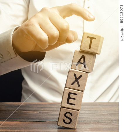 Businessman removes wooden blocks with the word Taxes. The concept of tax payment for housing and property. Income / goods tax. Avoidance. Burden Taxation. GST. Business and Finance. Selective focus 69512073