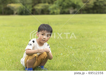 芝生でしゃがむ男の子の写真素材