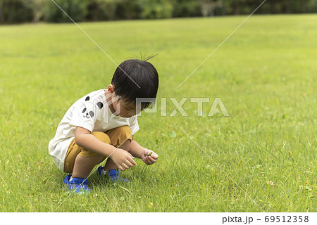芝生でしゃがむ男の子の写真素材