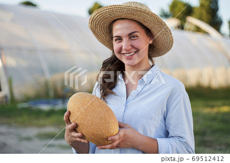Happy girl holding melon in hands Happy girl holding melon in hands 69512412