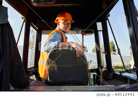Driver in hardhat siiting in tracktor 69512443
