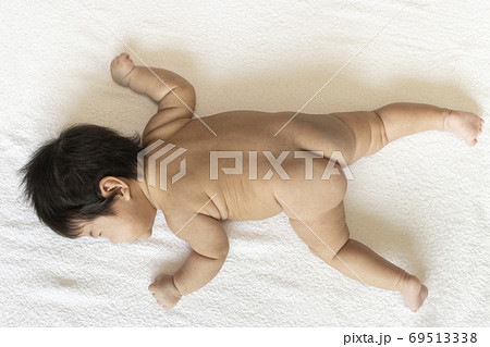 うつ伏せになっている生後2ヶ月の裸の赤ちゃんの全身の写真素材