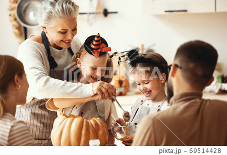 Multi generational family preparing for Halloween in kitchen. 69514428