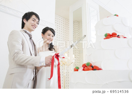 ケーキ入刀をする新郎新婦 69514536