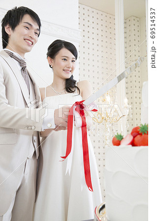 ケーキ入刀をする新郎新婦 69514537