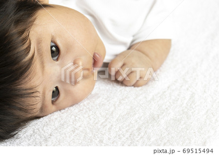 うつ伏せになっている生後2ヶ月の赤ちゃんの顔の写真素材