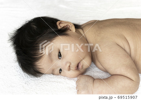 うつ伏せになっている生後2ヶ月の裸の赤ちゃんの顔の写真素材
