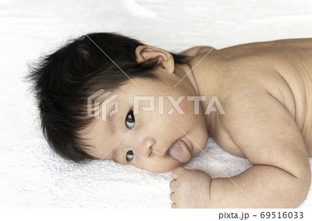 うつ伏せになっている生後2ヶ月の裸の赤ちゃんの顔の写真素材