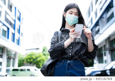 マスク姿で携帯電話をもつ若い女性 マスク姿で携帯電話をもつ若い女性 69516769