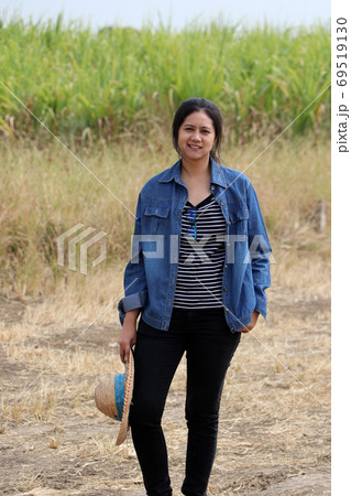 Woman agriculturist standing with straw hat in hand and wearing Woman agriculturist standing with straw hat in hand and wearing 69519130