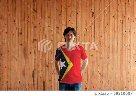 Man wearing Timor Leste flag color and standing with crossed beh Man wearing Timor Leste flag color and standing with crossed beh 69519607