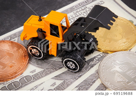 Miniature excavator, bitcoins as symbol of cryptocurrency and dollar, mining virtual money concept 69519688