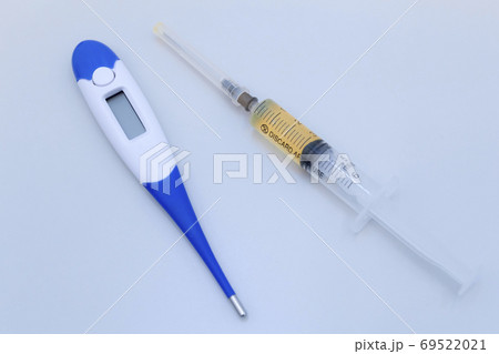 Medical equipment is spread out on the table, medicines and equipment on a grey surface, a thermometer for measuring temperature and syringe, 69522021