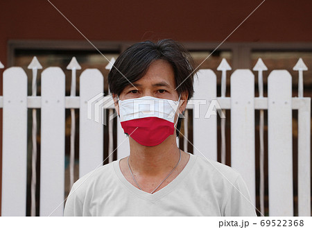 Poland flag on hygienic mask. Masked Asian man prevent germs. co Poland flag on hygienic mask. Masked Asian man prevent germs. co 69522368