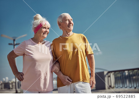 Two smiling pleased aged people standing outside 69522885
