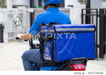 Delivery man wearing blue uniform riding motorcycle and delivery box. 69524008
