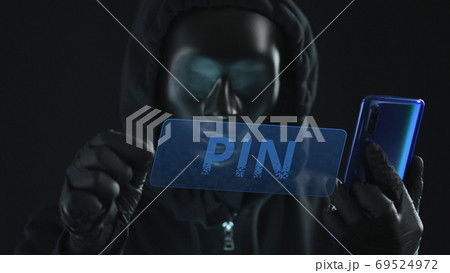 Hacker wearing black mask pulls PIN tab from a smartphone. Hacking concept Hacker wearing black mask pulls PIN tab from a smartphone. Hacking concept 69524972