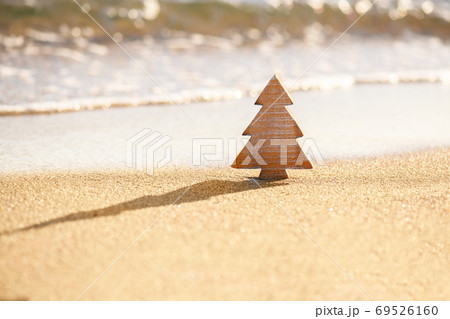 Timber wooden Christmas tree on a sand on the tropical beach near ocean, summer Christmas and winter holyday concept Timber wooden Christmas tree on a sand on the tropical beach near ocean, summer Christmas and winter holyday concept 69526160