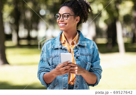 African Student Girl Using Cellphone Walking On Weekend In Park African Student Girl Using Cellphone Walking On Weekend In Park 69527642