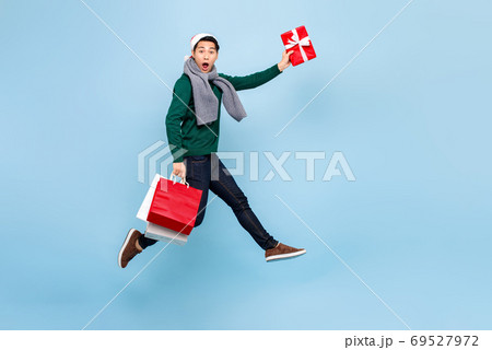 Asian man in Christmas attire jumping with red shopping bag and gift box Asian man in Christmas attire jumping with red shopping bag and gift box 69527972