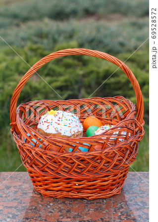 Easter cake and colorful Easter eggs in wicker basket Easter cake and colorful Easter eggs in wicker basket 69528572