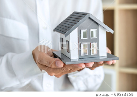 Image of Real estate broker agent sending house model to client 69533259