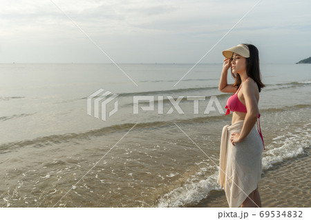 cheerful woman in bikini standing at sea beach 69534832