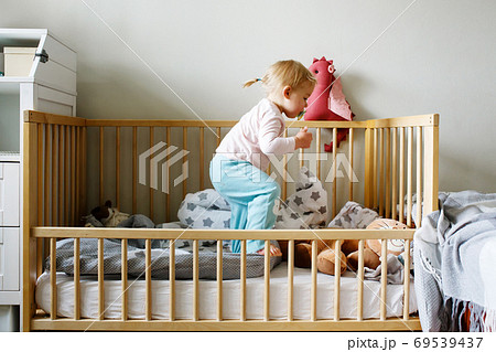 Cute funny little toddler girl playing in a crib Cute funny little toddler girl playing in a crib 69539437