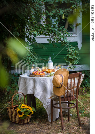 Summer table setting with homemade plum cake, milk, fruits, sunflowers in the basket Summer table setting with homemade plum cake, milk, fruits, sunflowers in the basket 69540895