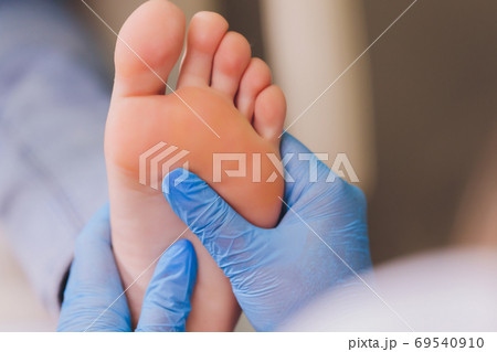 Therapist hands in protective gloves massaging woman's feet. Therapist hands in protective gloves massaging woman's feet. 69540910